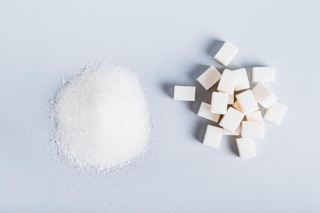 Granulated white sugar in a pile beside white sugar cubes — the same substance in different physical forms